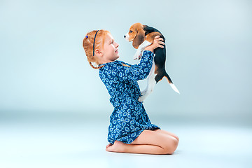 Image showing The happy girl and a beagle puppie on gray background