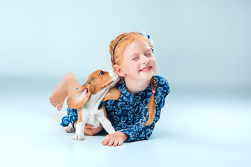 Image showing The happy girl and a beagle puppie on gray background