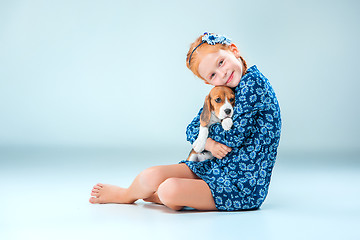 Image showing The happy girl and a beagle puppie on gray background