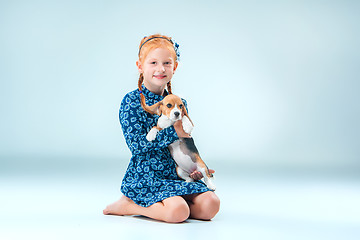 Image showing The happy girl and a beagle puppie on gray background