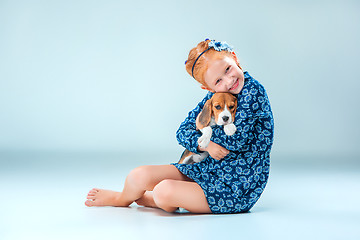 Image showing The happy girl and a beagle puppie on gray background