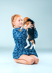 Image showing The happy girl and a beagle puppie on gray background