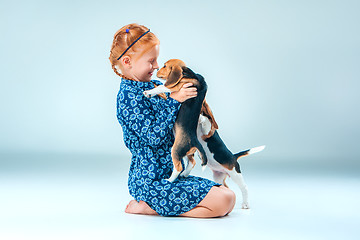 Image showing The happy girl and a beagle puppie on gray background