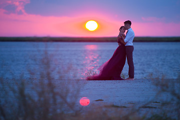 Image showing Young romantic couple relaxing on the beach watching the sunset