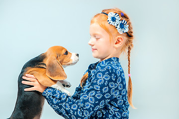 Image showing The happy girl and a beagle puppie on gray background