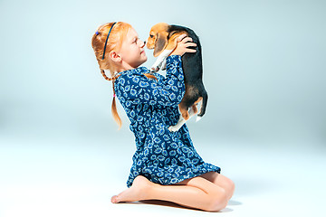 Image showing The happy girl and a beagle puppie on gray background