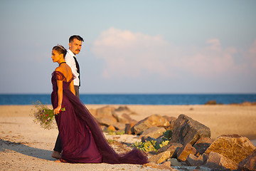 Image showing Young romantic couple relaxing on the beach watching the sunset