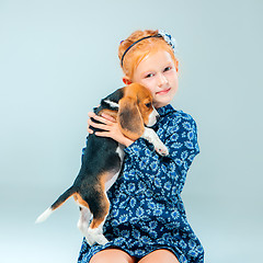 Image showing The happy girl and a beagle puppie on gray background