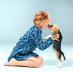 Image showing The happy girl and a beagle puppie on gray background