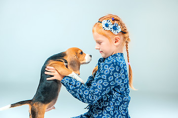 Image showing The happy girl and a beagle puppie on gray background