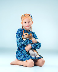 Image showing The happy girl and a beagle puppie on gray background