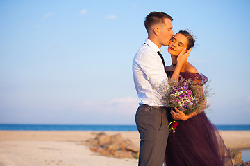 Image showing Young romantic couple relaxing on the beach watching the sunset