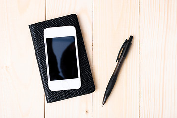 Image showing Small notepad with pen and smartphone