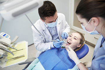 Image showing male dentist treating female patient teeth