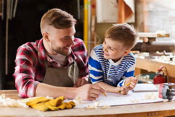 Image showing happy father and son with blueprint at workshop