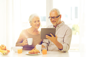 Image showing happy senior couple with tablet pc at home