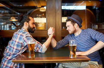 Image showing men drinking beer and arm wrestling at bar or pub