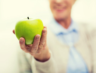 Image showing close up of senior woman hand holding green apple