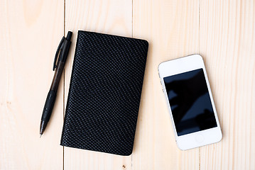 Image showing Small notepad with pen and smartphone