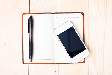 Image showing Small notepad with pen and smartphone