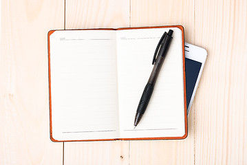 Image showing Small notepad with pen and smartphone
