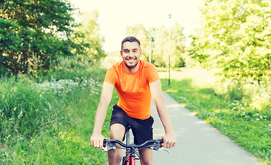 Image showing happy young man riding bicycle outdoors