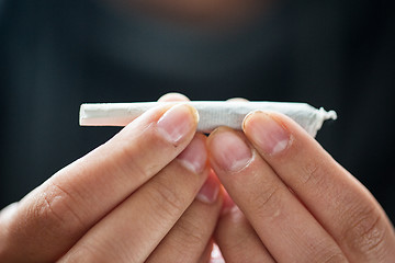 Image showing close up of addict hands with marijuana joint