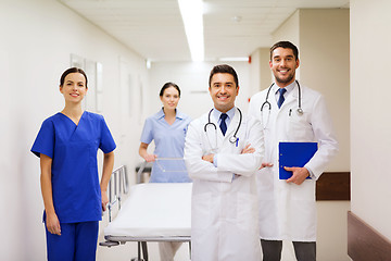 Image showing group of happy doctors with gurney at hospital