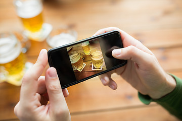 Image showing close up of hands with smartphone picturing beer