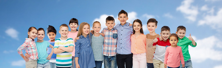 Image showing group of happy children hugging over blue sky