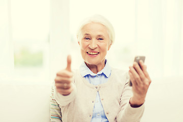 Image showing senior woman with smartphone showing thumbs up