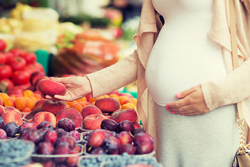 Image showing pregnant woman choosing fruits at street market