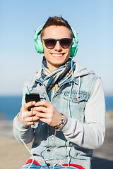 Image showing happy young man in headphones with smartphone