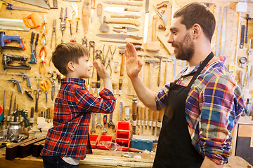 Image showing father and little son making high five at workshop