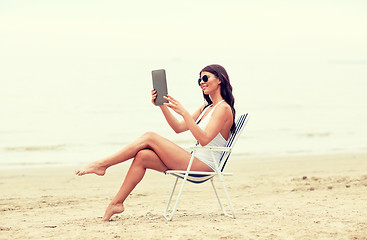 Image showing smiling woman with tablet pc sunbathing on beach