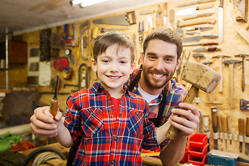 Image showing boy with dad holding chisel and hammer at workshop