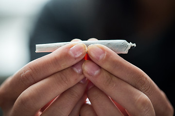 Image showing close up of addict hands with marijuana joint