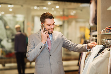 Image showing happy man calling on smartphone at clothing store