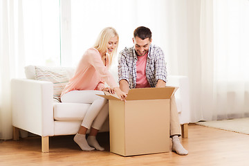 Image showing happy couple with cardboard box or parcel at home