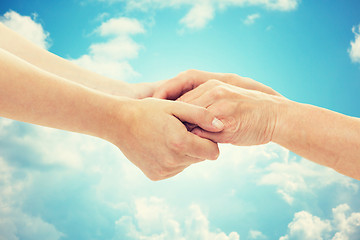 Image showing close up of senior and young woman holding hands