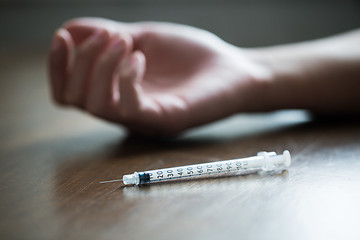 Image showing close up of addict hand and used drug syringe