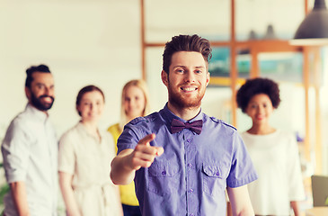 Image showing happy man pointing finger at you over office team