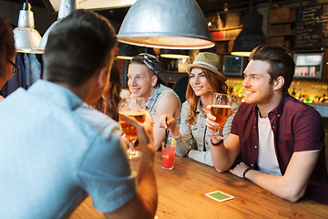 Image showing happy friends with drinks talking at bar or pub