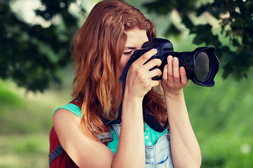 Image showing young woman with backpack and camera outdoors