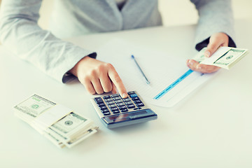 Image showing close up of hands counting money with calculator