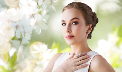 Image showing smiling woman in white dress with diamond jewelry