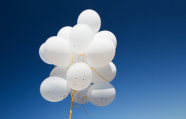 Image showing close up of white helium balloons in blue sky