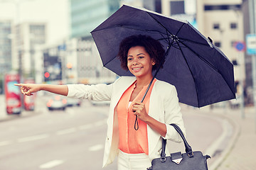 Image showing happy african woman with umbrella catching taxi