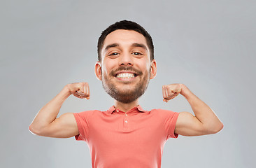 Image showing smiling man showing biceps over gray background