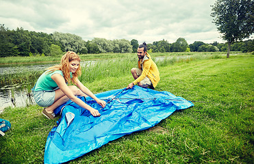 Image showing happy couple setting up tent outdoors